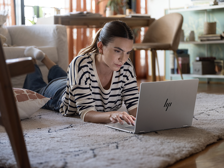 Frau arbeitet mit HP OmniBook X Flip 16 auf dem Teppich