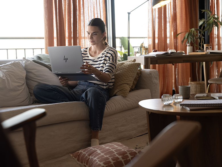 Frau nutzt HP OmniBook X Flip 16 im Zeltmodus auf dem Sofa